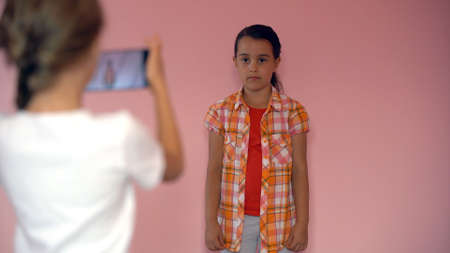 two little girls taking photo with a smartphoneの写真素材