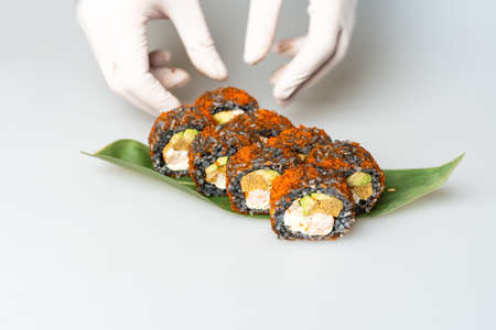 Cook hands making japanese sushi roll. Japanese chef at work preparing delicious sushi roll with eel and avocado. Appetizing japanese food.の写真素材