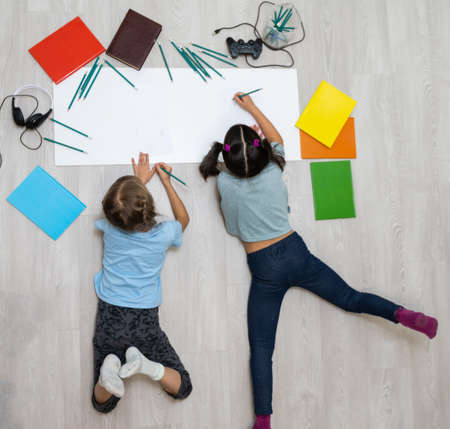 Cute children are painting and smiling while lying on the floor at homeの写真素材
