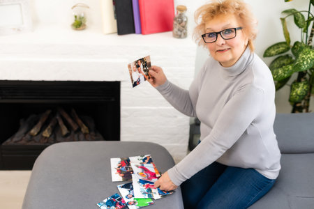 an elderly woman is looking at a photo of her grandchildrenの写真素材