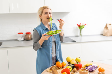 healthy eating, dieting and people concept - close up of young woman eating vegetable salad at homeの写真素材