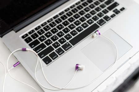 laptop keyboard with headphones and diary on tableの写真素材