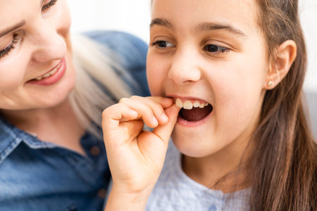 Cute young child holding her tooth which may be loose or aching