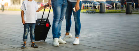 Let journey begin. Portrait of cute couple with their son at airport walking down hall with suitcasesの写真素材