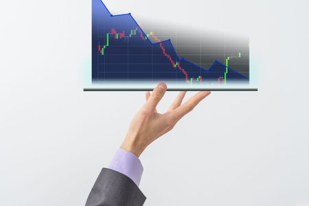 Businessmans hand holds a stock graph display in a visual screen. It shows signs of falling stocks...