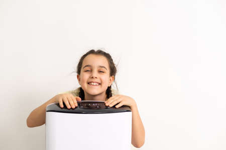 Cute little girl standing breathing at air purifier. Clean air conceptの写真素材