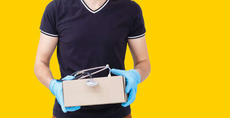 delivery man carrying paper bag with food products isolated over yellow backgroundの写真素材