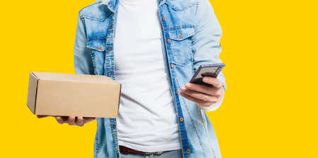 delivery man carrying paper bag with food products isolated over yellow backgroundの写真素材