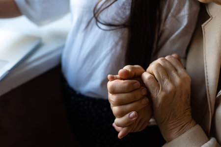 Unrecognizable grandmother and her granddaughter holding hands.の写真素材