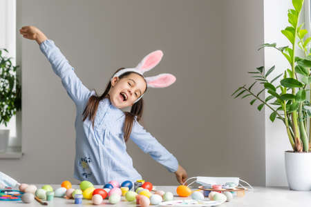Cute little child wearing bunny ears on Easter day. Girl with painted eggsの写真素材