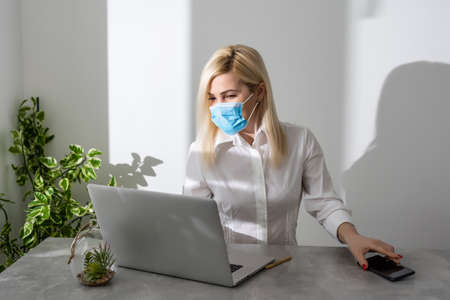 Young business woman working from home, wearing protective maskの写真素材