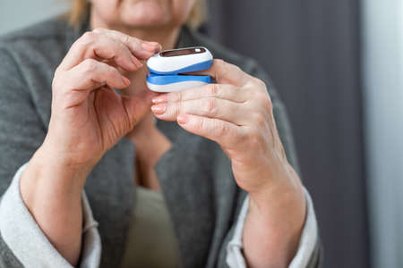 Old lady measuring her oxygen saturation with a pulse oximeter. Health conceptの写真素材