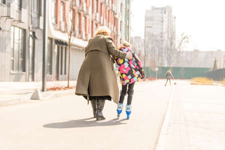 grandmother teaches granddaughter to roller skateの写真素材