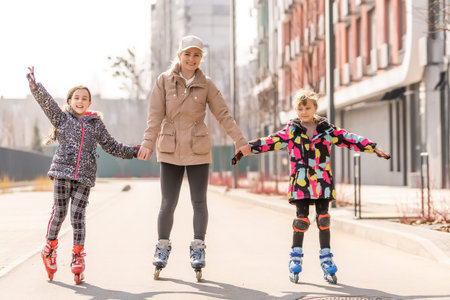 Family rollerskating in park. Active walk. Preschool girl having active walk with her mother
