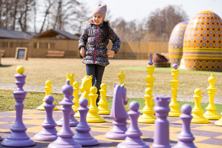 cute little girl playing with giant chess outdoorsの写真素材