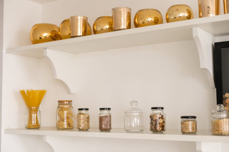 stocked kitchen pantry with food, jars and containers of cereals, jam, coffee, sugar, flour, oil,...