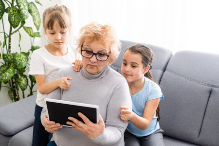 Grandmother with young girl use touch screen tablet computer smiling