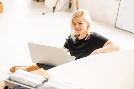Happy casual beautiful woman working on a laptop sitting in the house.の写真素材