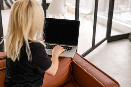 Happy casual beautiful woman working on a laptop sitting in the house.の写真素材