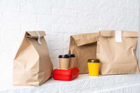 Fast food packaging set. Paper coffee cups in holder, food box, brown paper bag on the tableの写真素材
