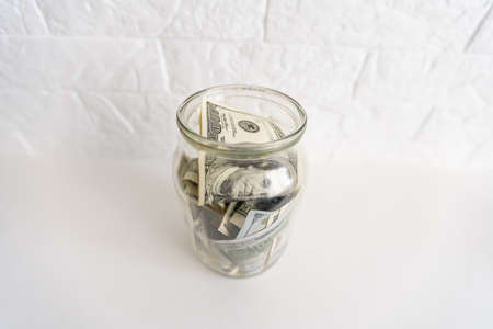 One hundred dollar bills in a glass jarの写真素材