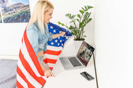 woman holding usa flag and video by laptopの写真素材