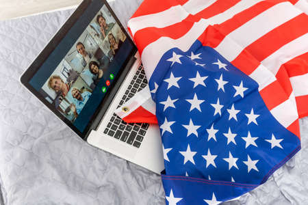 Young woman with USA flag using a laptop computer, independence day onlineの写真素材