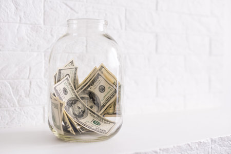 One hundred dollar bills in a glass jar