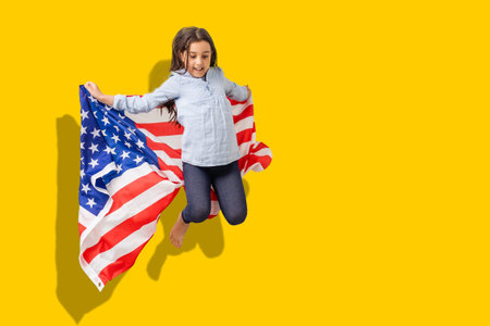 happy child girl with flag of the United States of America USA on yellow color background