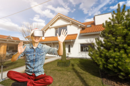 Cheerful man in virtual glasses in front of new house