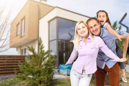Happy family. family on the background of a new house. Modern new house is on the background.の写真素材