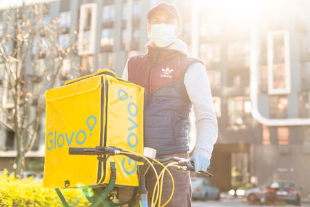 KIEV, UKRAINE - 28 April, 2021: Glovo delivery boy with famous yellow box and bicycle on the street. delivery service worker on bikeのeditorial素材