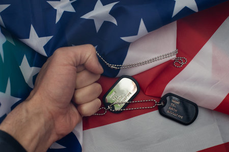 Dog tags lies with hand of man.
