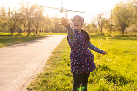 Child playing with plane. Happy girl play outdoorsの写真素材