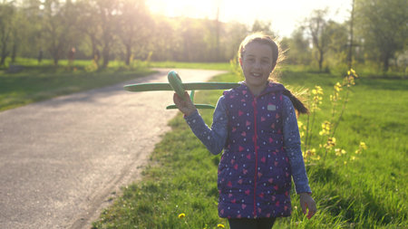 Child playing with plane. Happy girl play outdoors