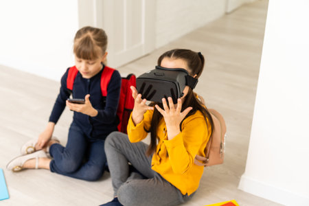 full length view of two multicultural schoolgirls holding hands while using virtial reality headsets on white backgroundの写真素材