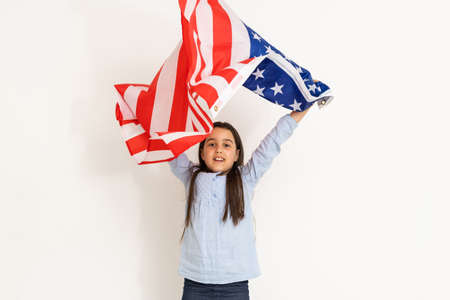 Patriotic holiday. Happy kid, cute little child girl with American flag. USA celebrate 4th of July.の写真素材