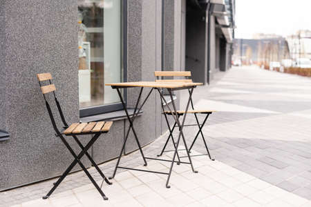 The photo shows a table and chairs on an open terrace near the cafeの写真素材