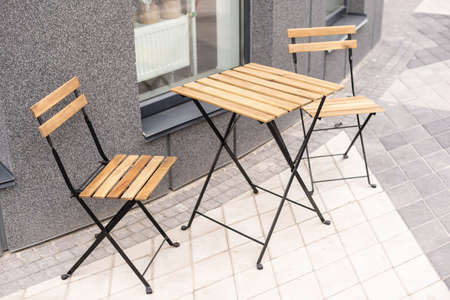The photo shows a table and chairs on an open terrace near the cafeの写真素材