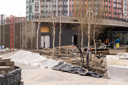 A landscape worker digging a trench during an irrigation system installation project in a yard by a quiet residential streetの写真素材
