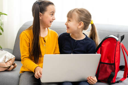 Cute girl friends laughing at laptop computer screen, hugging.の写真素材