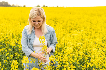 Portrait of young beautiful woman in blooming rapeseed meadow