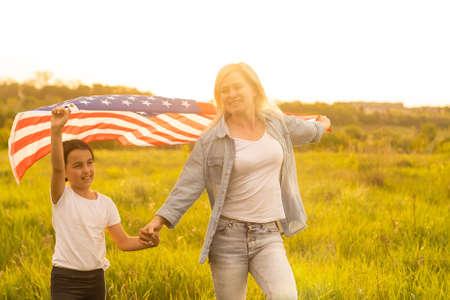 Mother and daughter with American Flag in a beautiful fieldの写真素材