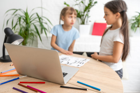 little girl learning chinese while using her laptop computer in the living room at home. family...