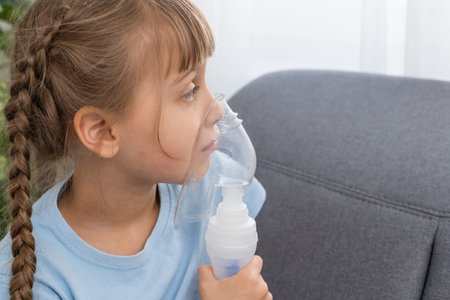 Little girl making inhalation with nebulizer at home. child asthma inhaler inhalation nebulizer...