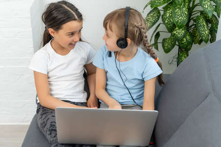 Little girls at home with laptop, video chatting with their friends.の写真素材