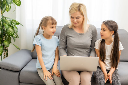 Smiling mother with young kids using laptop at home