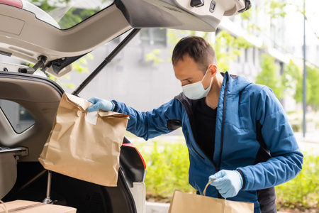 delivery man in a medical mask and gloves delivers the parcel