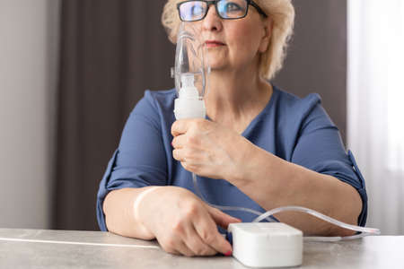 Elderly woman using asthma machine at homeの写真素材
