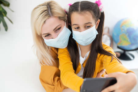 Little girl and her young mother taking a selfie wearing surgical mask.の写真素材